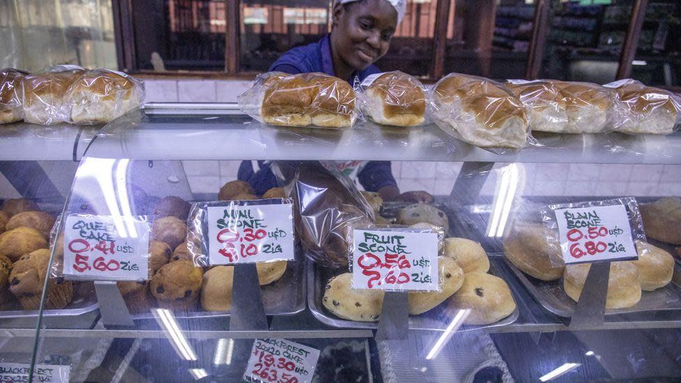 A supermarket worker at a bakery counter, where the prices are shown in US dollars and Zimbabwean Zigs, Harare, Zimbabwe - 30 April 2024