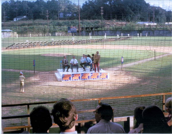 A Sept. 26, 1970 rally for the Reubin Askew campaign for governor held at Centennial Field in Tallahassee. Askew is in a blue shirt on the dais leaning over to touch the shoulder of his running mate for Lt. Governor, [1961-1971 Secretary of State] Tom Adams. Centennial Field, built in 1924 for Tallahassee's 100th anniversary and demolished in 1975, served as the capital city's chief sports and civic arena for decades. The site, off South Monroe Street, is now Cascade Park.