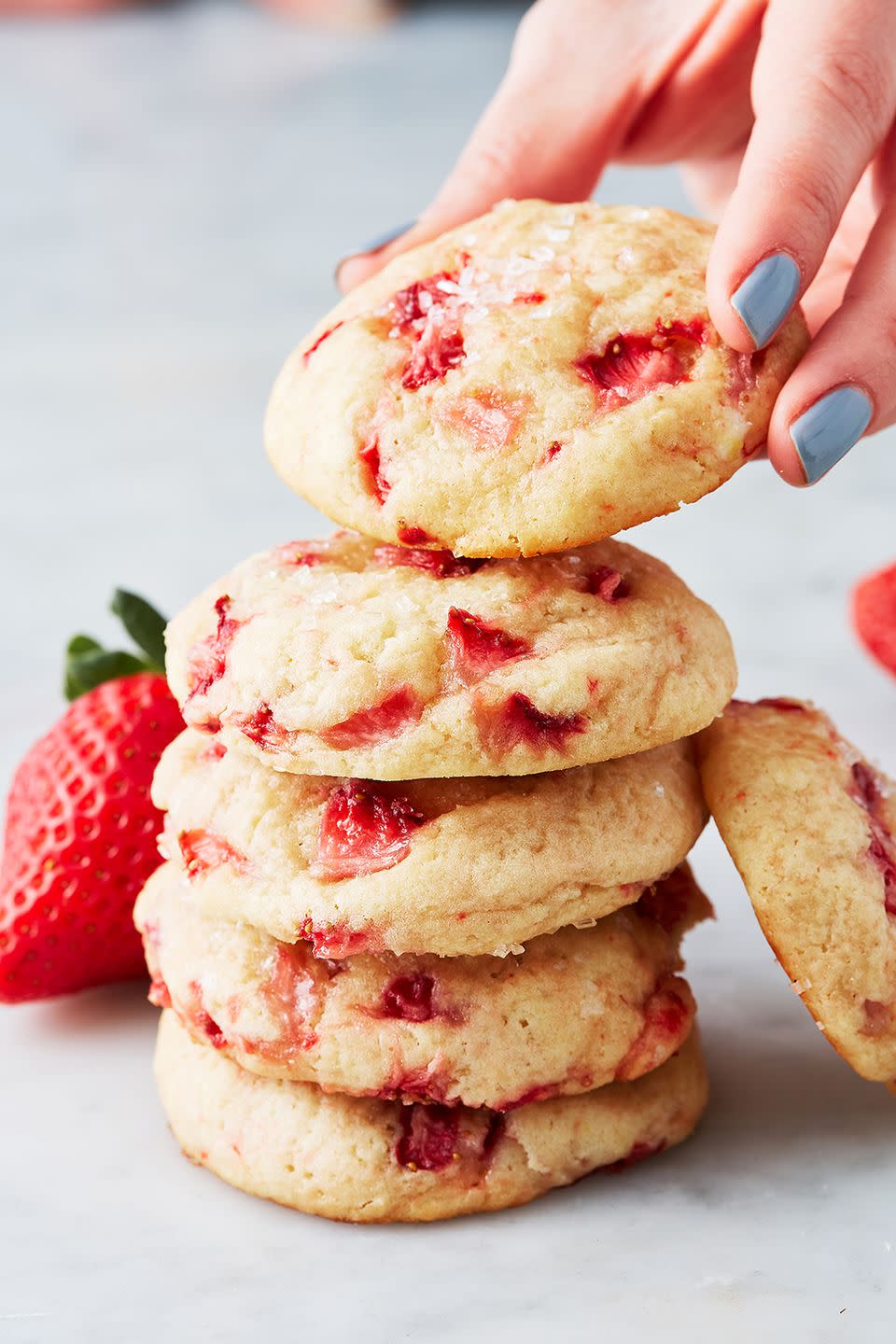 6 strawberry shortcake cookies in a stack next to a fresh strawberry