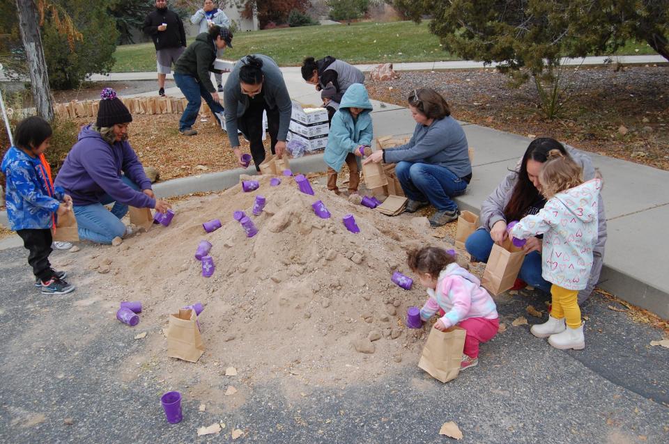 Students, staff members and their children from the Child and Family Development Center at San Juan College fill sacks with sand on Dec. 1 in preparation for this weekend's luminarias display on the college campus in Farmington.