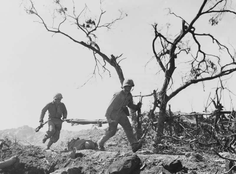 U.S. Marines pass the body of a Japanese soldier while under fire on Iwo Jima