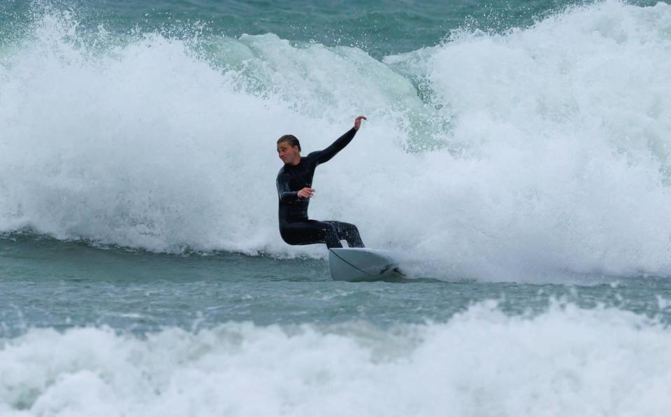 A surfer takes advantage of the weather by the Bal Harbour Lighthouse on Thursday, Dec. 14, 2023 in Bal Harbour, Fla. The gusty winds, heavy rain, flooded streets and other hazards are expected continue over the weekend in Miami, Fort Lauderdale and Palm Beach.