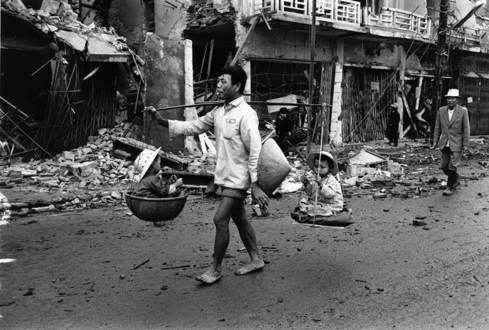 <p>A Vietnam War refugee returns to Hue, carrying two children in baskets suspended from his shoulder in March 1968. (Photo: Terry Fincher/Daily Express/Hulton Archive/Getty Images) </p>