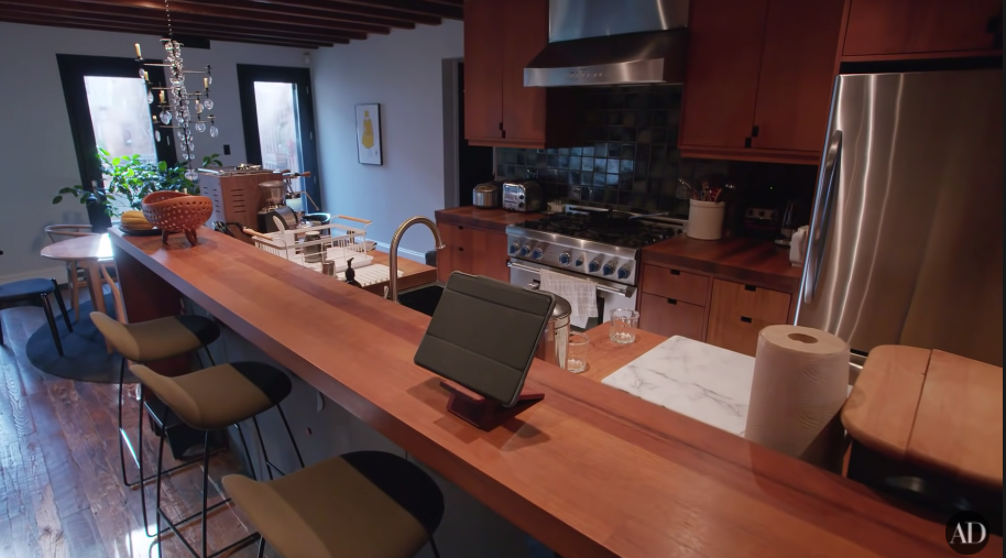 A kitchen with a long, narrow island and dark wood floors