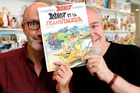 Author Jean-Yves Ferri (L) and illustrator Didier Conrad (R) pose with a copy of their new comic album "Asterix et la Transitalique" (Asterix and the Chariot Race) after an interview in Vanves near Paris, France, October 17, 2017, the latest in the series created by illustrator Albert Uderzo and writer Rene Goscinny in 1959. Picture taken October 17, 2017. REUTERS/Philippe Wojazer