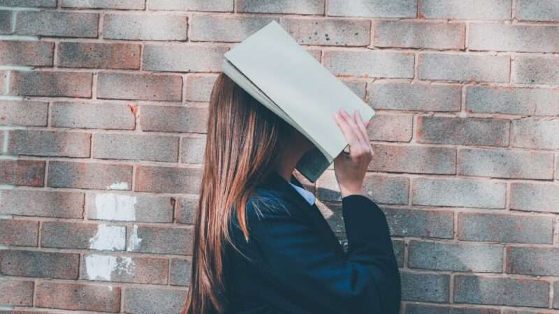 high school girl with book over her face