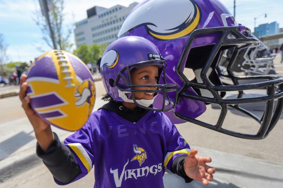 Camden Lake, 4, of Detroit, poses in front of the Minnesota Vikings helmet during the NFL Draft Experience in downtown Detroit on Friday, April 26, 2024.