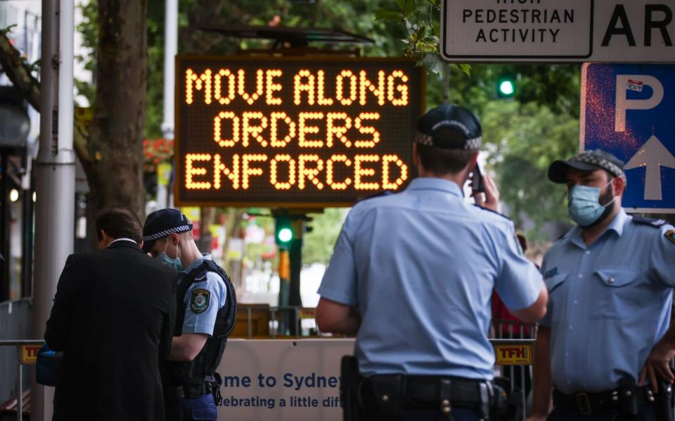 New South Wales police officers guard an entrance as part of Covid-19 restrictions for New Year celebrations around Circular Quay in central Sydney - David Gray/AFP