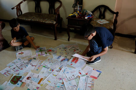 Gabriel Moncada looks at his drawings on the floor at his home in Caracas, Venezuela October 15, 2018. REUTERS/Marco Bello