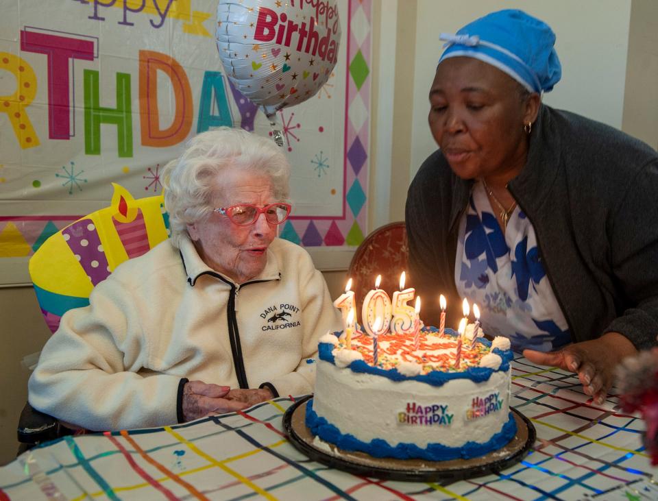 Agnes DeCenzo, 105, a resident at Waterview Lodge Rehabilitation & Healthcare in Ashland, gets some help from Assistant Director of Nursing Kiseme Kimba in blowing out candles on her cake, Feb. 15, 2023. DeCenzo is the last surviving original participant of the Framingham Heart Study.