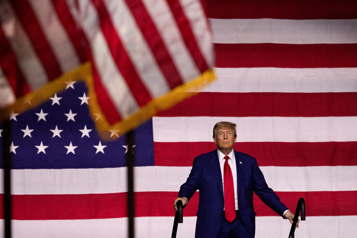 Former President Donald Trump with a gigantic American flag behind him.