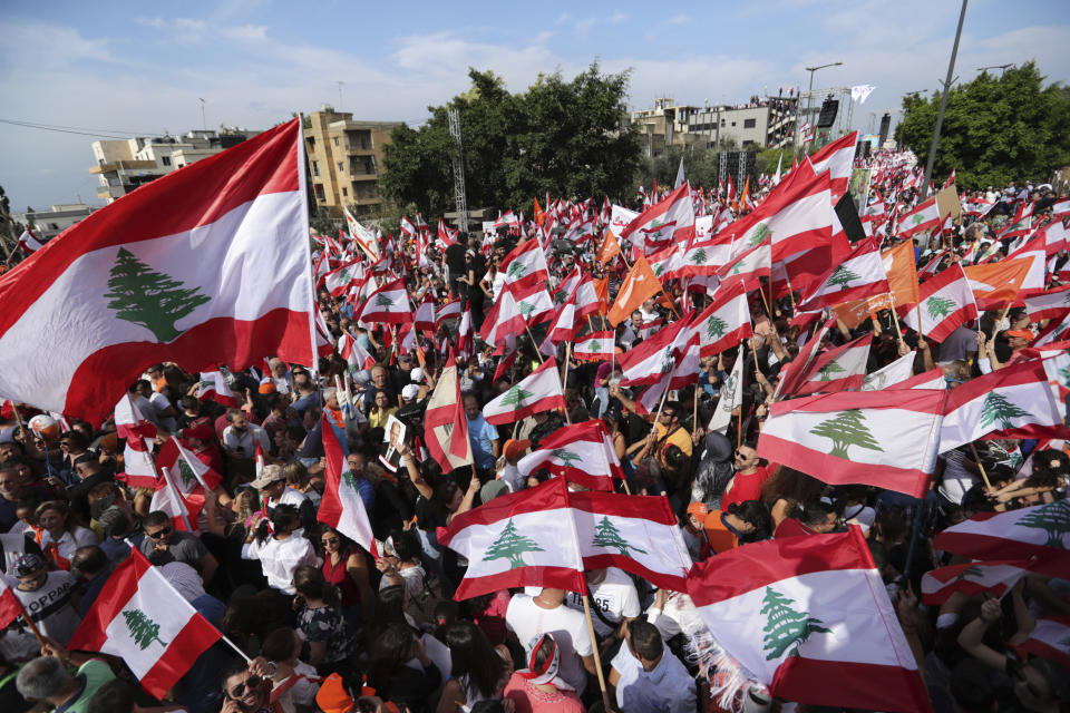 Supporters of Lebanese President Michel Aoun hold Free Patriotic Movement Party and Lebanese flags during a protest near the presidential palace in the Beirut suburb of Baabda, Lebanon, Sunday, Nov. 3, 2019. Thousands of people are marching to show their support for Aoun and his proposed political reforms that come after more than two weeks of widespread anti-government demonstrations. (AP Photo/Hassan Ammar)