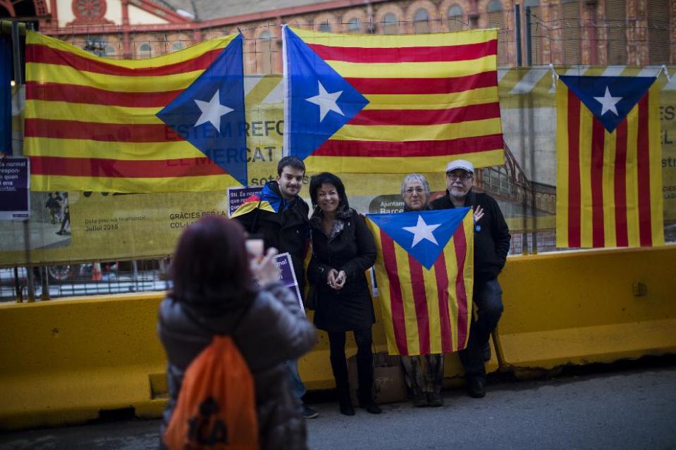 In this photo taken on Sunday, Jan. 12, 2014, people pose for a photograph next to an "estelada" flag during a pro-independence event in Barcelona, Spain. After years of mass protests by Catalans demanding the right to decide whether they want to break away from Spain and form a new European nation, the wealthy northeastern region’s lawmakers vote to ask permission from Spanish authorities to hold a secession referendum in November. The request eight months ahead of a Scottish independence referendum is certain to be denied by the central government in Madrid but is virtually guaranteed of generating even more separatist fervor. (AP Photo/Emilio Morenatti)