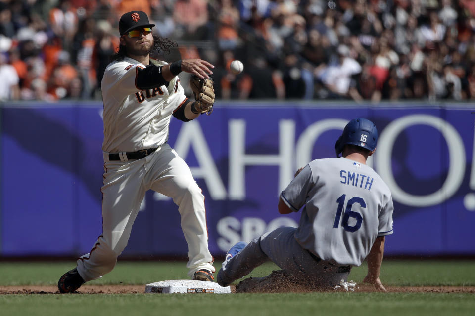 San Francisco Giants shortstop Brandon Crawford, left, throws to first base after forcing Los Angeles Dodgers' Will Smith (16) out at second base during the third inning of a baseball game in San Francisco, Sunday, Sept. 29, 2019. (AP Photo/Jeff Chiu)