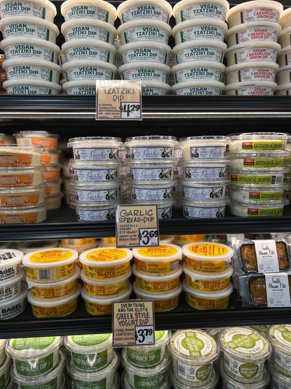 Shelves stocked with various dips and spreads, including tzatziki and garlic spread, with pricing labels