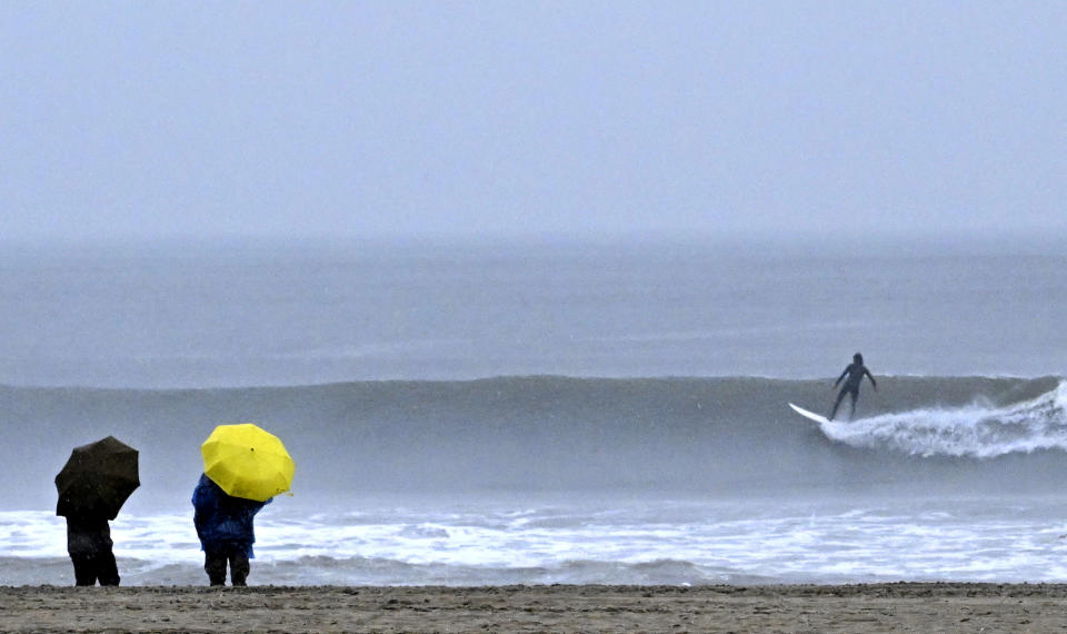 People walk along the beach as surfers brave the waves during a rain storm at Venice Beach in Los Angeles on Saturday, Jan. 14, 2023. (Keith Birmingham/The Orange County Register via AP)