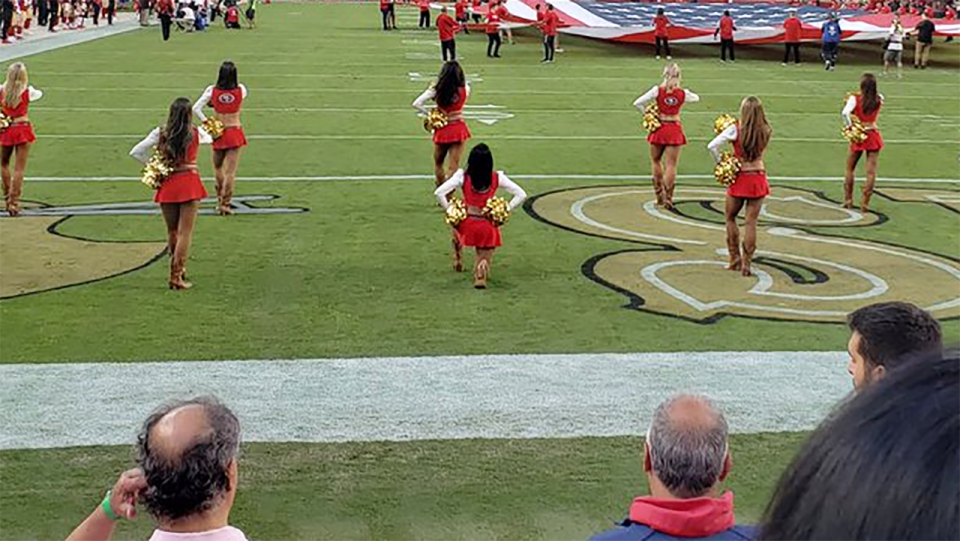 A San Francisco 49ers cheerleader has caused a stir by taking a knee during the national anthem. Pic: @GatorLenny/Twitter