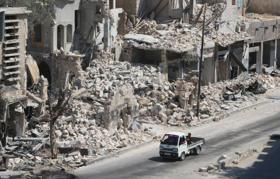 Men ride on a pick-up truck past damaged buildings in the rebel-held Bab al-Hadid neighbourhood of Aleppo, Syria on Aug. 18, 2016.