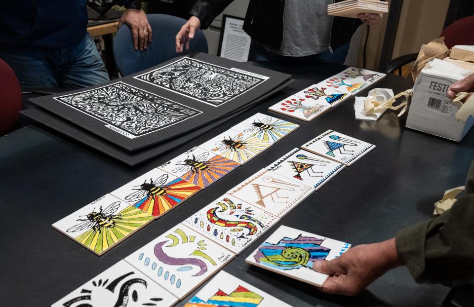South Phoenix-based artists Emily Costello (center) and Martin Moreno (right) look at hand-painted tiles that will part of the Roeser Road light rail station, January 10, 2023, at E2 Innovations in Phoenix, Arizona.