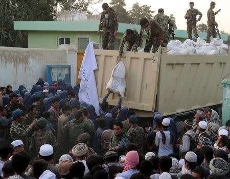 Afghan National Army troops distribute aid to the civilians of Kunduz, Afghanistan October 14, 2015. The Taliban said they were pulling back in the northern city of Kunduz on Tuesday in order to protect civilians, but fighting continued elsewhere in the country with government troops battling to reopen the main highway south of the capital Kabul. REUTERS/Stringer