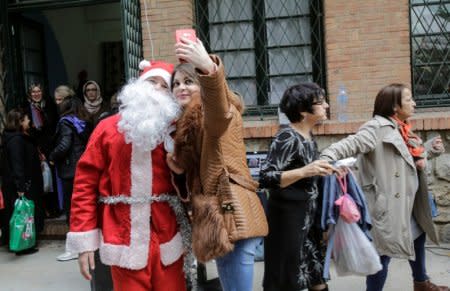 A woman takes a selfie with a man dressed as Santa Claus at a Christmas market in Algiers, Algeria December 15, 2017. Picture taken December 15. 2017. REUTERS/Ramzi Boudina