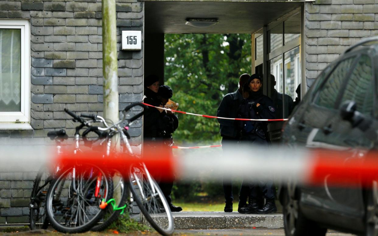 Police stand outside the block of flats where the bodies were discovered - THILO SCHMUELGEN /REUTERS