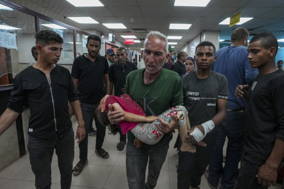 A Palestinian brings a child wounded in the Israeli bombardment of the Gaza Strip into a hospital in Deir al Ballah on Wednesday, June 5, 2024. (AP Photo/Abdel Kareem Hana)