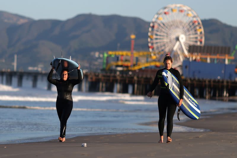 Surfers walk on the beach on the first day of the opening of LA County beaches in Santa Monica