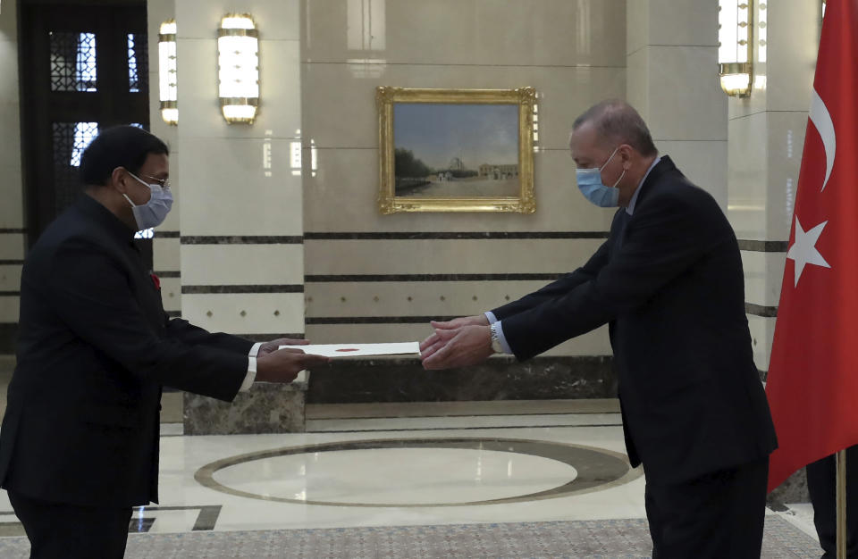 Turkey's President Recep Tayyip Erdogan, wearing a face mask to protect against the spread of coronavirus, receives a letter of credentials from the new ambassador of India, Sanjay Kumar Panda, during a ceremony at the presidential palace, in Ankara, Turkey, Wednesday, Aug. 19, 2020. Turkey has reported 1,303 new confirmed cases of the coronavirus _ the highest daily jump in more than a month.(Turkish Presidency via AP, Pool)