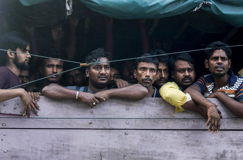 Men from Bangladesh ride in the back of a truck heading to an immigration detention center in Medan, North Sumatra, Indonesia, Wednesday, Feb. 6, 2019. Officials said a few dozen men were found locked in a house, waiting for a broker to bring them illegally by boat to Malaysia, with some planning to work on palm oil plantations. (AP Photo/Binsar Bakkara)