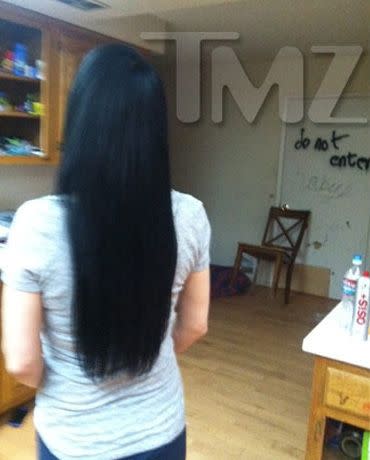 Nadya Suleman showing off her new hairstyle. In the background, a chair is wedged under the doorknob and graffiti can be seen on the walls. Credit: TMZ.com