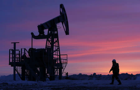 FILE PHOTO: A worker walks past a pump jack on an oil field owned by the Bashneft company near Nikolo-Berezovka, Bashkortostan, Russia , January 28, 2015. REUTERS/Sergei Karpukhin/File Photo