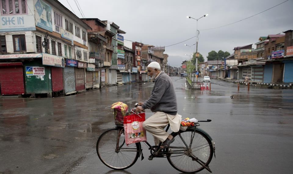 A Kashmiri man rides a bicycle through a deserted street during security lockdown in Srinagar, Indian controlled Kashmir, Wednesday, Aug. 14, 2019. India has maintained an unprecedented security lockdown to try to stave off a violent reaction to Kashmir's downgraded status. Protests and clashes have occurred daily, thought the curfew and communications blackout have meant the reaction is largely subdued. (AP Photo/ Dar Yasin)