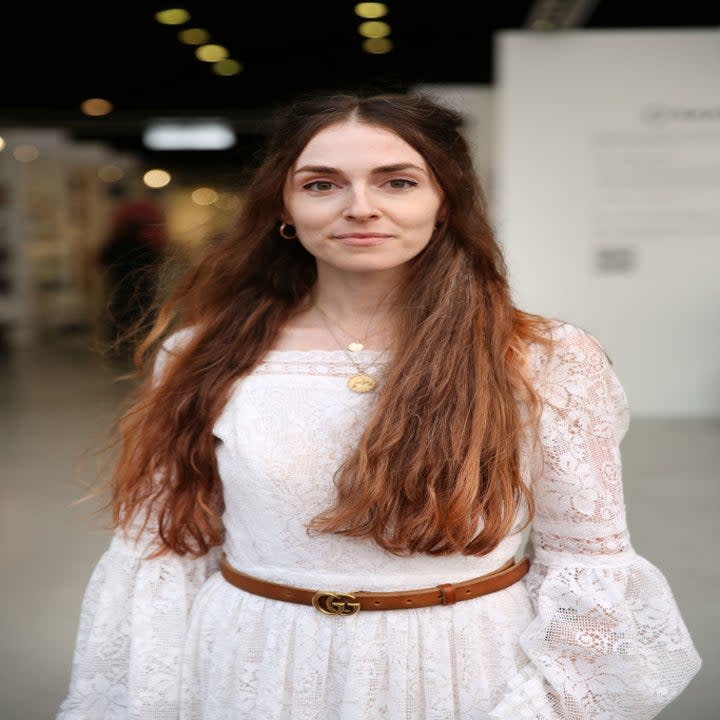 Anna in a lacy white long-sleeve dress and belt