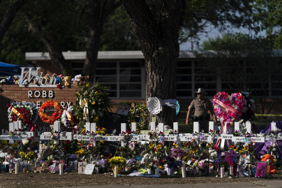 FILE - Flowers and candles are placed around crosses on May 28, 2022, at a memorial outside Robb Elementary School in Uvalde, Texas, to honor the victims killed in the school shooting a few days prior. A federal lawsuit was filed Wednesday, Sept. 28, 2022, in Del Rio, Texas, against eight entities and three individuals for the May shooting that killed 19 students and two teachers at the elementary school. (AP Photo/Jae C. Hong, File)