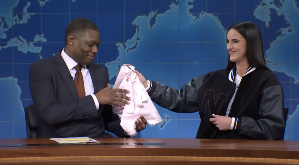 Caitlin handing Michael a signed apron on "SNL"