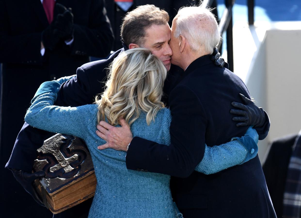 President Biden and first lady Jill Biden hug Hunter, who is holding a bible