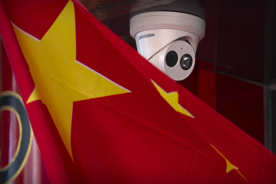 A Chinese flag hangs near a Hikvision security camera outside of a shop in Beijing, Tuesday, Oct. 8, 2019. The United States is blacklisting a group of Chinese tech companies that develop facial recognition and other artificial intelligence technology that the U.S. says is being used to repress China's Muslim minority groups. (AP Photo/Mark Schiefelbein)