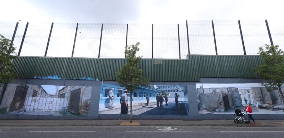 A woman walks past a Belfast peace wall (Niall Carson/PA) (PA Archive)