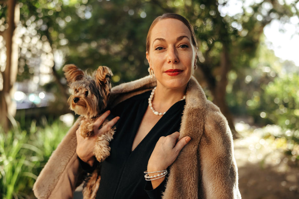 woman carrying a small dog and wearing a fur coat