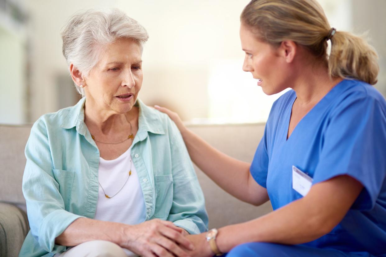 senior woman talking with nurse while sitting on couch