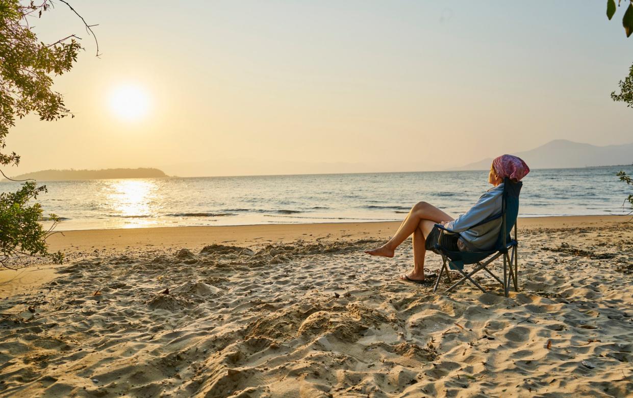 Woman on beach in deckchair looking away at sea