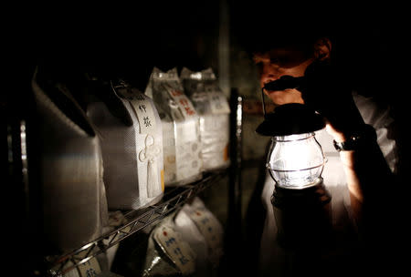 Kazuyuki Kitami, a city official of Yokosuka, holds a lantern as he visits a facility which keeps the unclaimed burial urns containing ashes of the dead in Yokosuka, Japan September 11, 2018. Picture taken September 11, 2018. REUTERS/Kim Kyung-Hoon