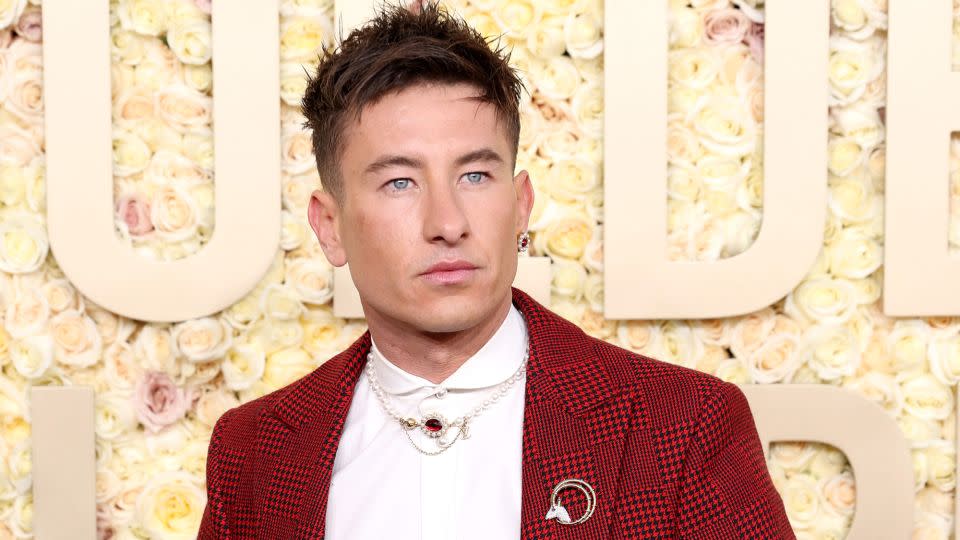 Barry Keoghan sported a red wool evening jacket in Louis Vuitton’s signature Damier pattern. He completed the look with checkered red pants from the label’s Spring-Summer 2024 collection, complete with a pearl belt chain, necklace, earring and a Tiffany & Co. broach. - Kevin Mazur/Getty Images