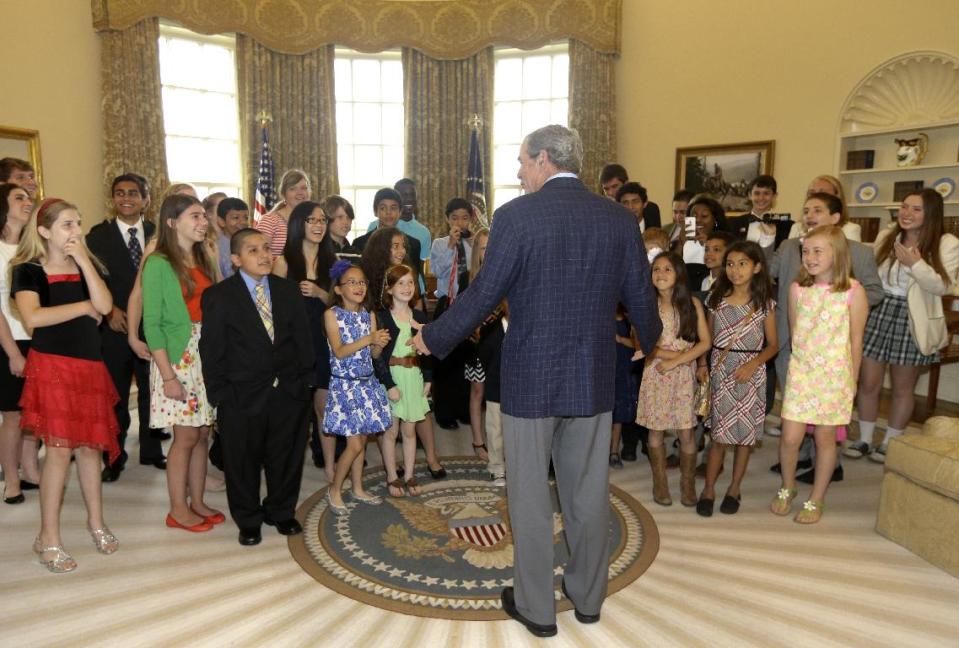 Former President George W. Bush, center, surprises 43 Dallas-Fort Worth area school children in the replica of the oval office at the Bush Presidential Library Wednesday, May 1, 2013, in Dallas. The students were the first official guest of the museum on its' opening day. (AP Photo/Tony Gutierrez)