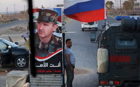 Syrian army soldier stands at a check-point as Russian military police vehicle, right, passes by near the village of Almajdiyeh, Syria, - Credit: AP