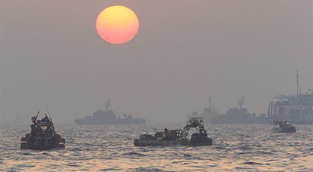 The orange sun begins to set above searchers and divers looking for bodies of passengers believed to have been trapped in the sunken ferry Sewol in the water off the southern coast near Jindo, south of Seoul, South Korea. Photo: AP.