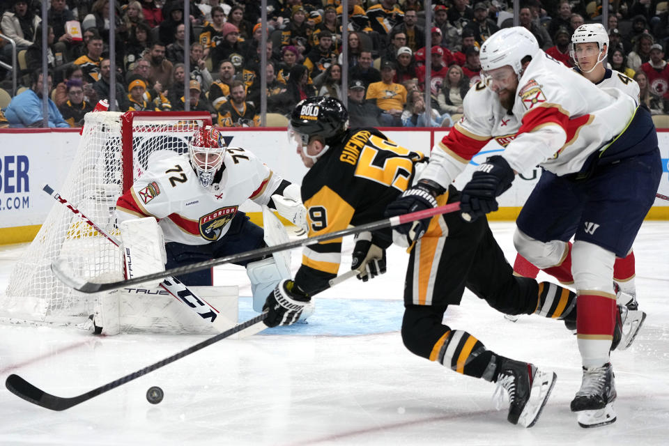 Pittsburgh Penguins Jake Guentzel (59) is checked off the puck by Florida Panthers' Aaron Ekblad, right, before he can get a shot off in front of goalie Sergei Bobrovsky (72) during the second period of an NHL hockey game in Pittsburgh, Wednesday, Feb. 14, 2024. (AP Photo/Gene J. Puskar)