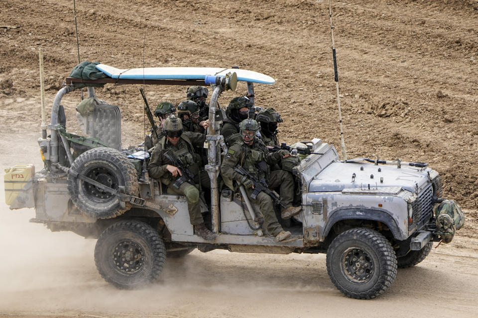 Israeli soldiers with a surfboard on the roof of their vehicle drive towards the Gaza Strip, in southern Israel, Tuesday, Feb. 13, 2024. The army is battling Palestinian militants across Gaza in the war ignited by Hamas' Oct. 7 attack into Israel. (AP Photo/Ariel Schalit)