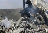 <p>A Syrian soldier sprays water on the wreckage of a building described as part of the Scientific Studies and Research Center (SSRC) compound in the Barzeh district, north of Damascus, during a press tour organised by the Syrian information ministry, on April 14, 2018. (Photo: Louai Beshara/AFP/Getty Images) </p>